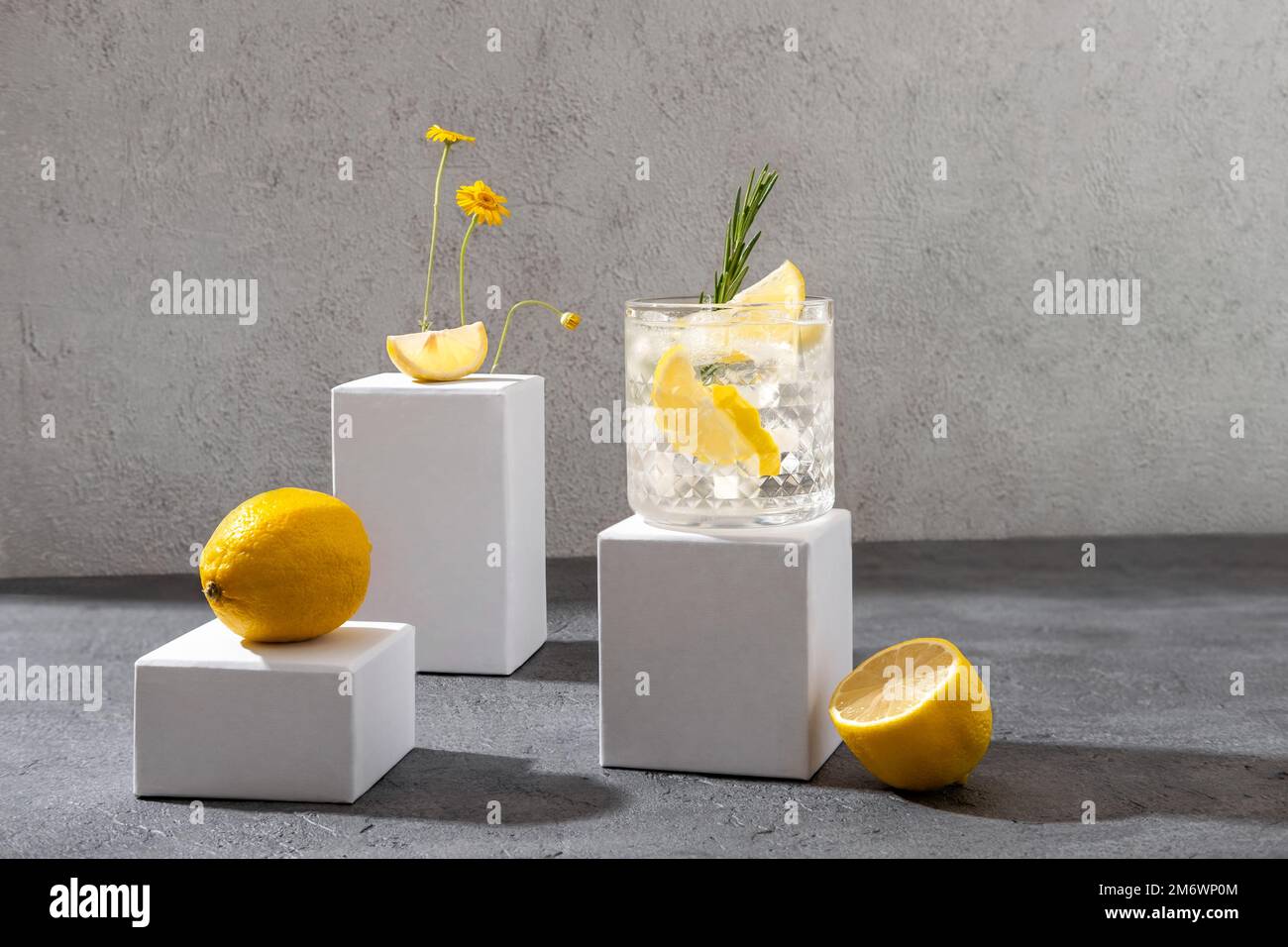 Sommercocktail mit Gin Tonic auf dem weißen Podium. Harter Seltercocktail mit Zitrone. Stockfoto
