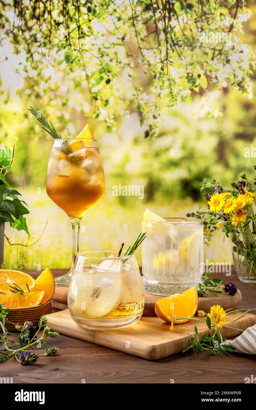 Drei farbenfrohe Sommercocktails auf dem Tisch. Starke Seltercocktails mit verschiedenen Früchten: Birne, Orange und Zitrone. Outdoor summ Stockfoto