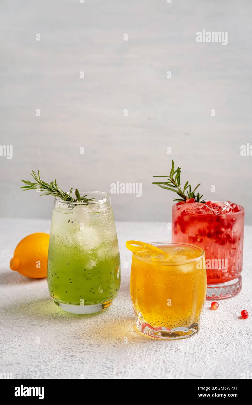 Drei farbenfrohe Sommercocktails in Gläsern auf einem weißen Tisch. Auswahl an frischen Sommergetränken. Rote Sangria-Cocktails, Orangenpunsch Stockfoto