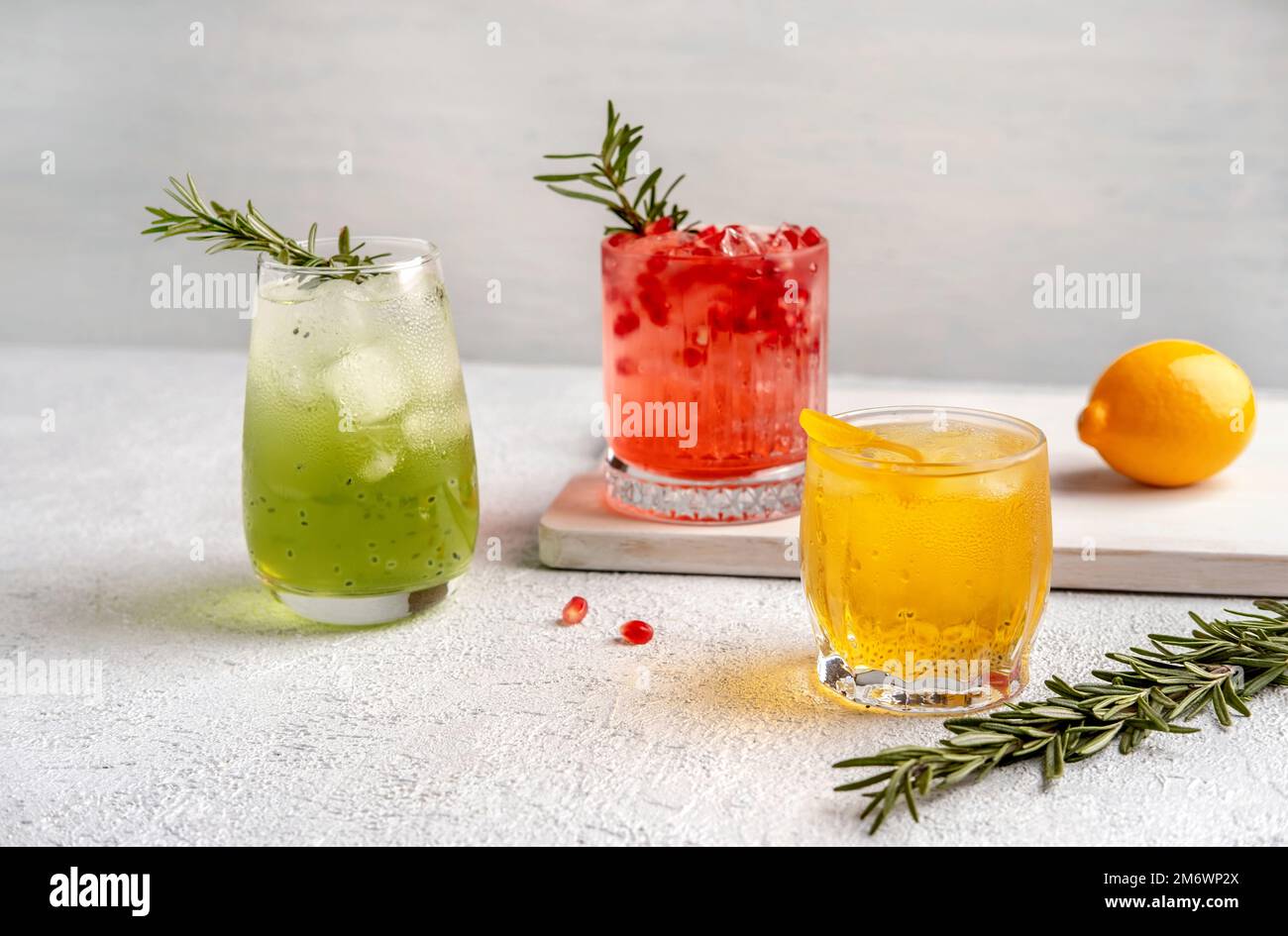 Drei farbenfrohe Sommercocktails in Gläsern auf einem weißen Tisch. Auswahl an frischen Sommergetränken. Rote Sangria-Cocktails, Orangenpunsch Stockfoto