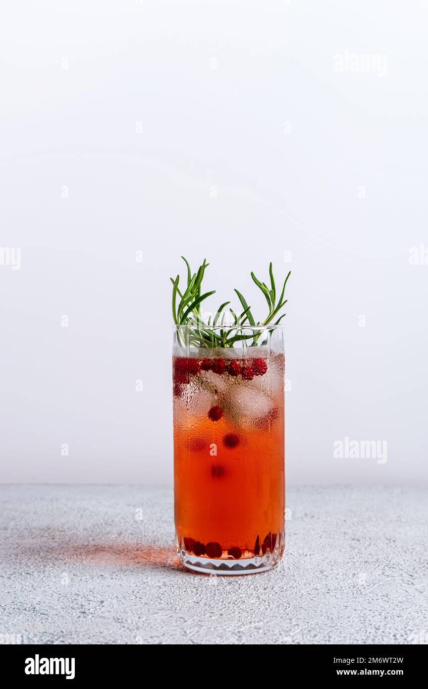 Cranberry und Rosmarin Gin Tonic. Farbenfroher Weihnachtscocktail in Glas auf weißem Tisch. Frische Feiertagsgetränke. Stockfoto
