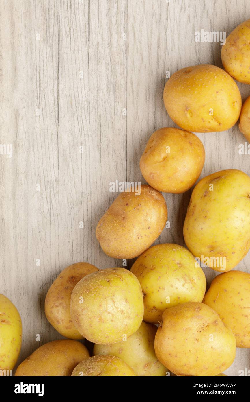 Ein Hintergrund mit Frühkartoffeln oder Babykartoffeln auf einem Holztisch Stockfoto