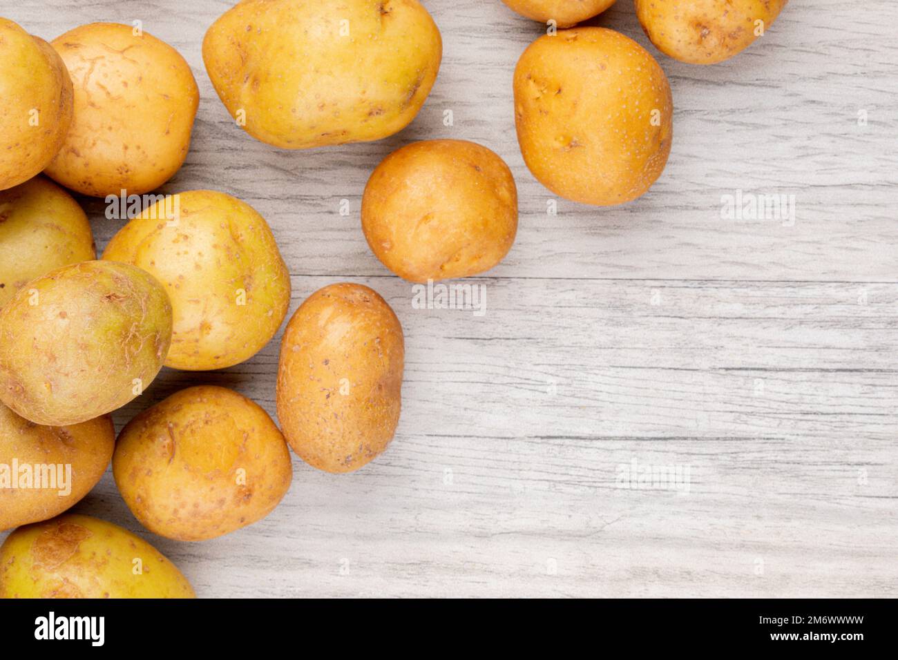 Ein Hintergrund mit Frühkartoffeln oder Babykartoffeln auf einem Holztisch Stockfoto