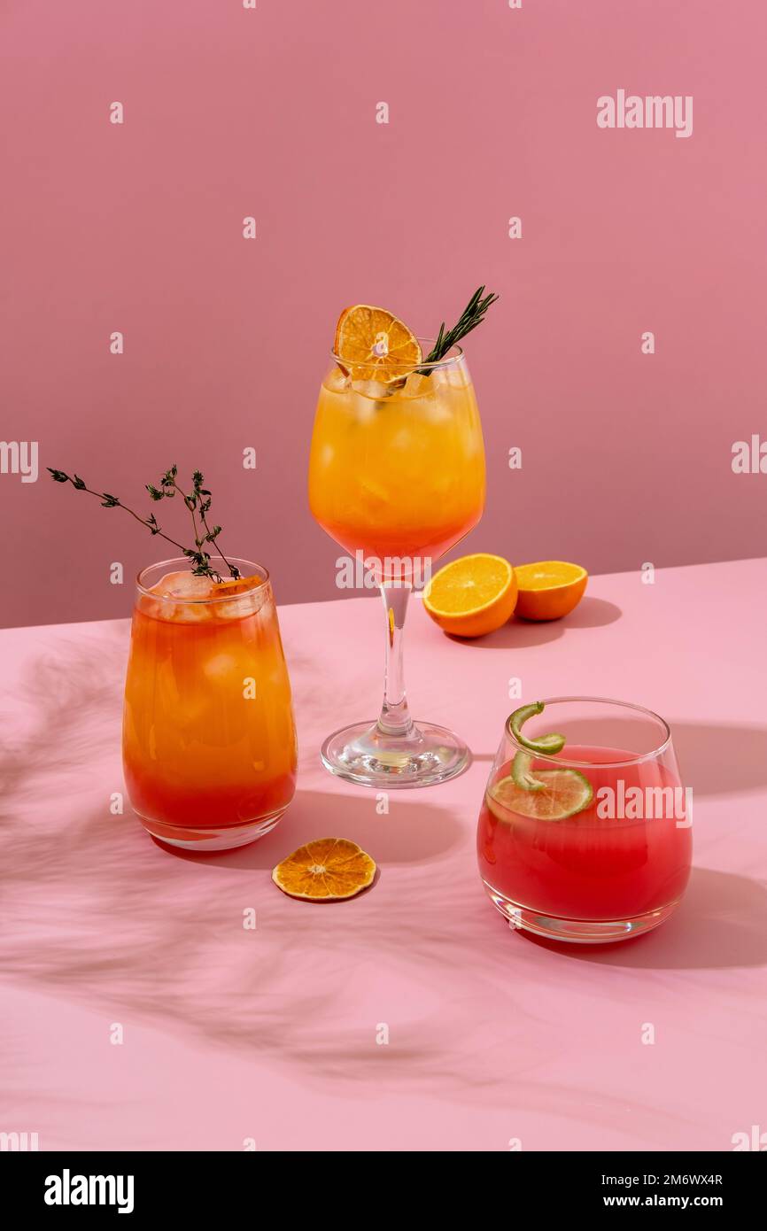 Farbenfrohe tropische Cocktails. Erfrischende, farbenfrohe Sommergetränke auf pinkfarbenem Hintergrund mit Palmenblättern. Getränkekarte an der Bar. Stockfoto