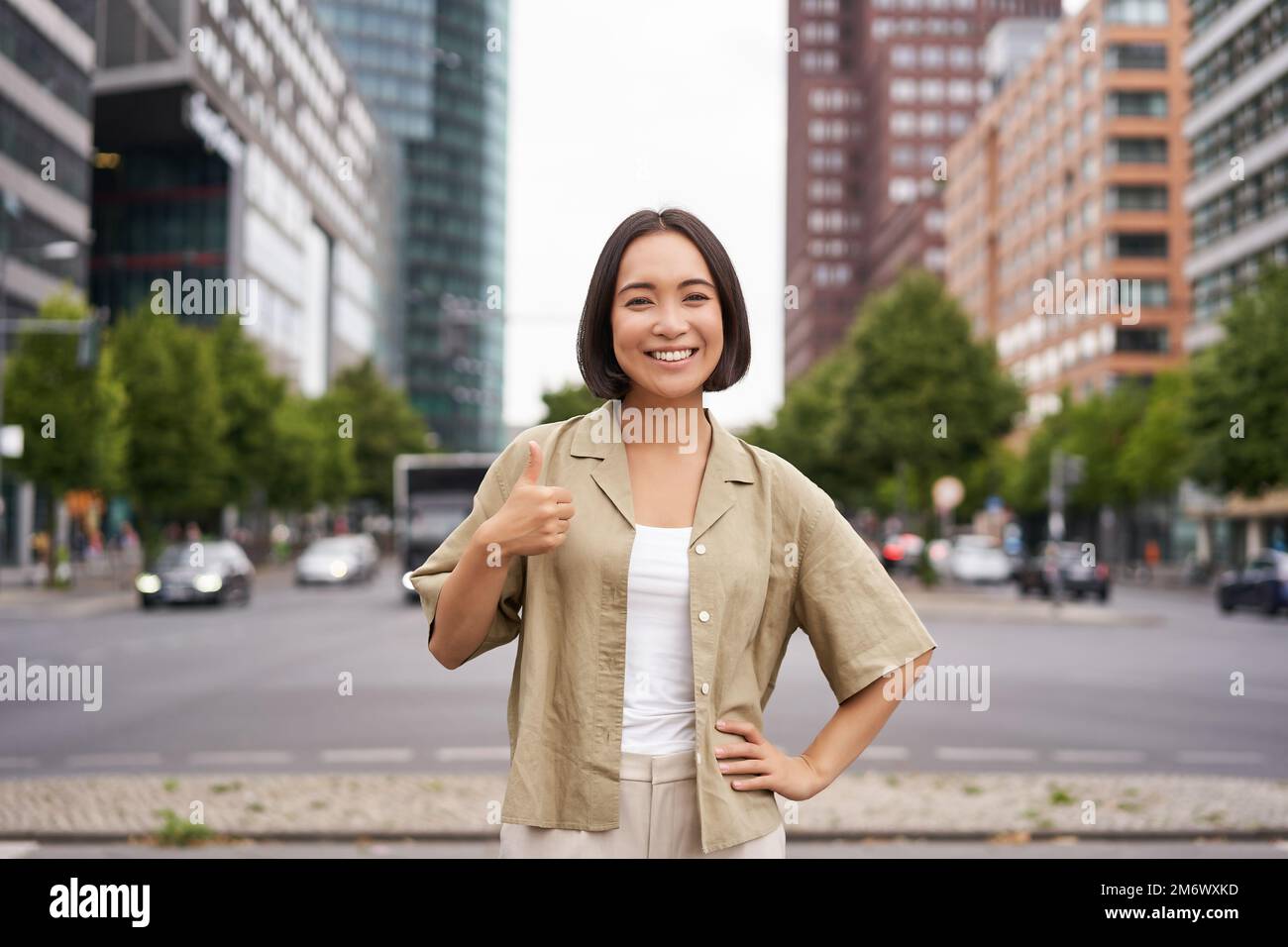 Enthusiastisches Stadtmädchen, zeigt Anerkennung, sieht optimistisch aus, sagt Ja, stimmt zu, steht auf der Straße Stockfoto