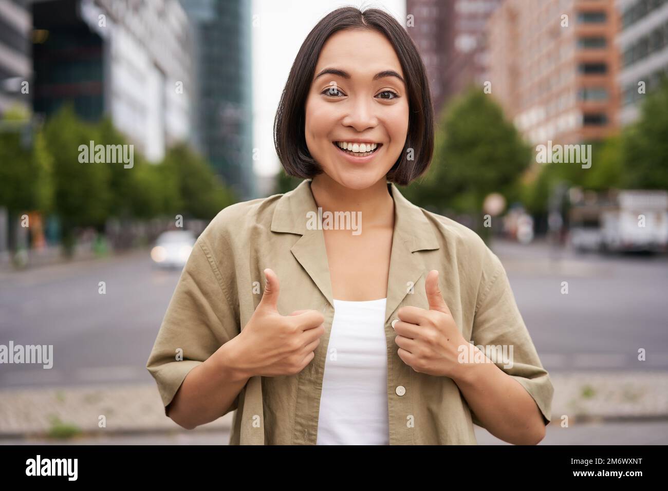 Enthusiastisches Stadtmädchen, zeigt Anerkennung, sieht optimistisch aus, sagt Ja, stimmt zu, steht auf der Straße Stockfoto