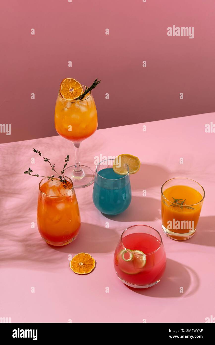 Farbenfrohe tropische Cocktails. Erfrischende, farbenfrohe Sommergetränke auf pinkfarbenem Hintergrund mit Palmenblättern. Getränkekarte an der Bar. Stockfoto