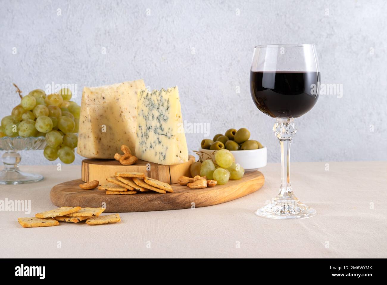 Glas Rotwein mit Trauben und Käse auf hellem Tischhintergrund. Rotwein mit Käse und Obst. Platz für Text Stockfoto