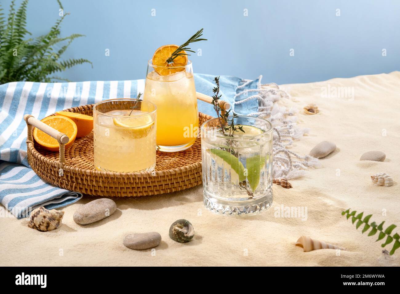 Auswahl an sommerlichen alkoholischen Cocktails auf einem Korbblech am Strand mit weißem Sand. Sommerurlaub und Reisekonzept. Exoti Stockfoto