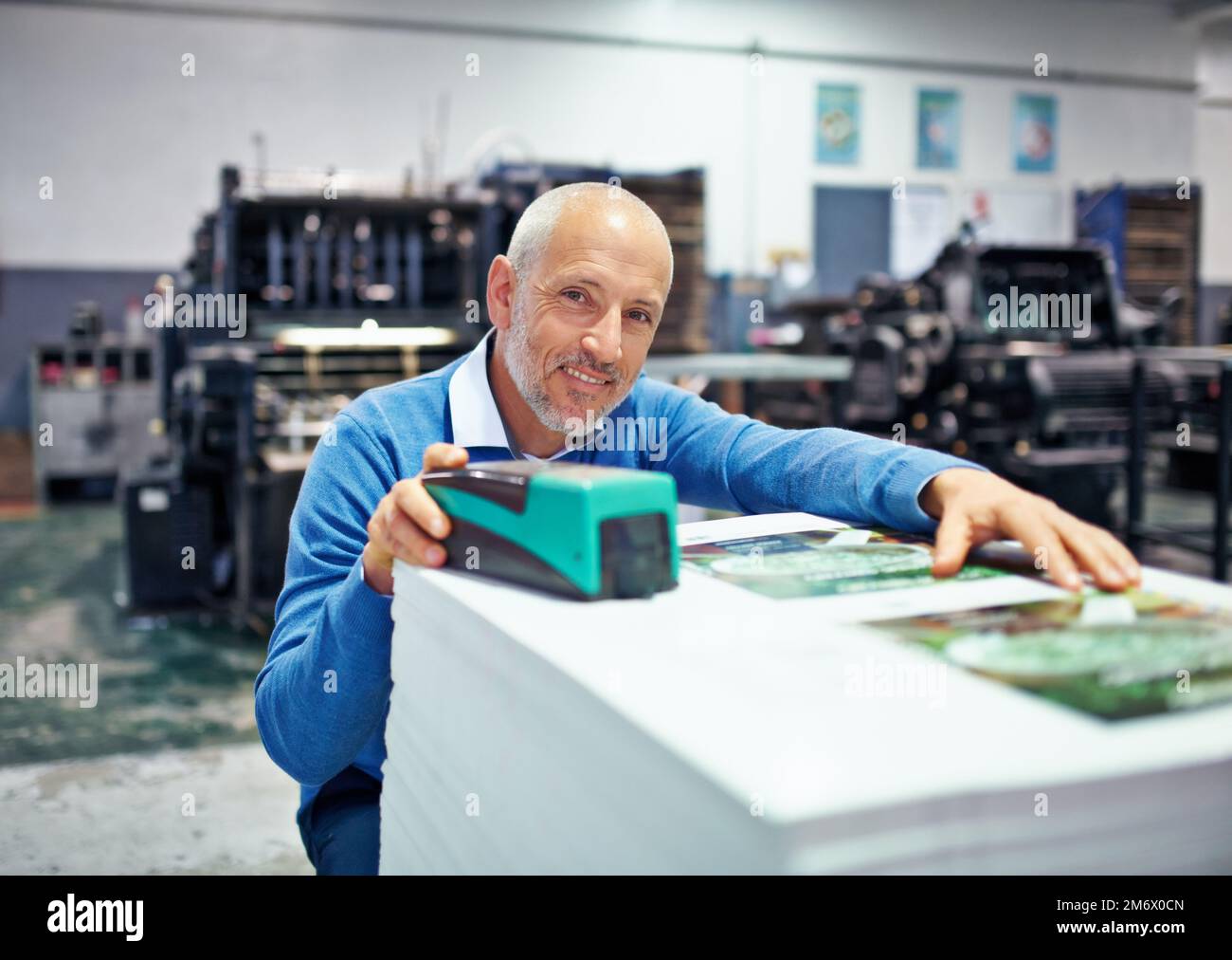 Ich habe immer das letzte Wort. Porträt eines Mannes, der die Qualität eines Druckdurchlaufs in einer Fabrik prüft. Stockfoto