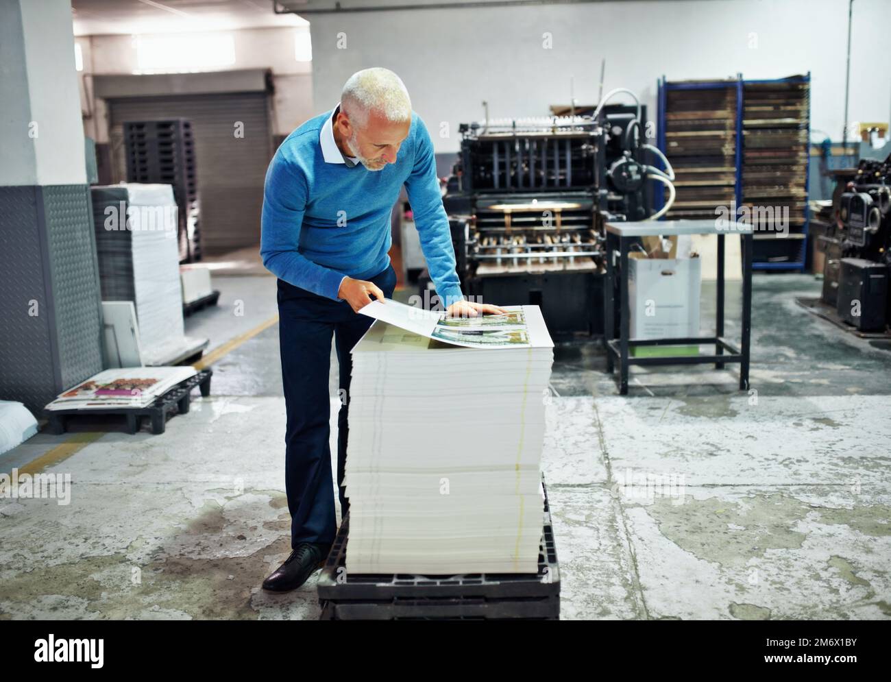 Überprüfen des Drucks auf Fehler. Ein Mann, der die Qualität eines Druckdurchlaufs in einer Fabrik prüft. Stockfoto
