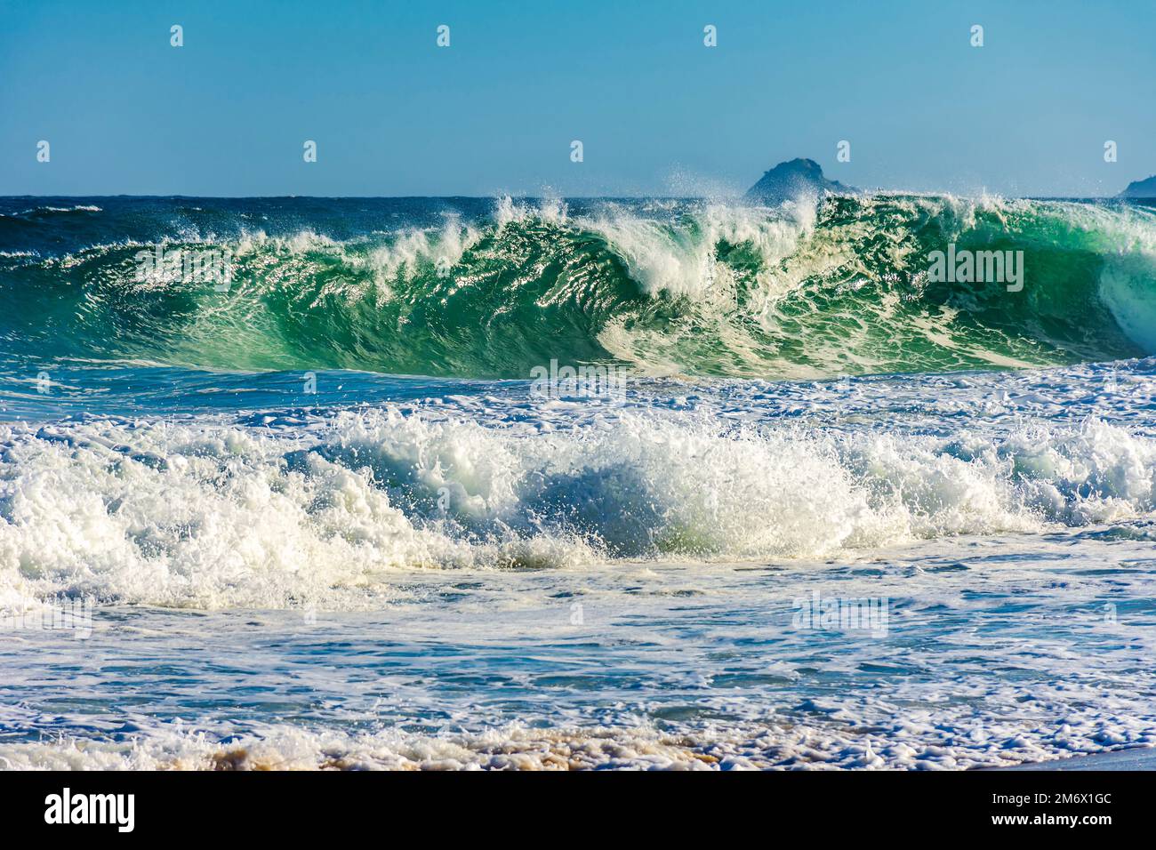 An einem sonnigen Tag im Sommer stürzt die Meereswelle am Strand ab Stockfoto