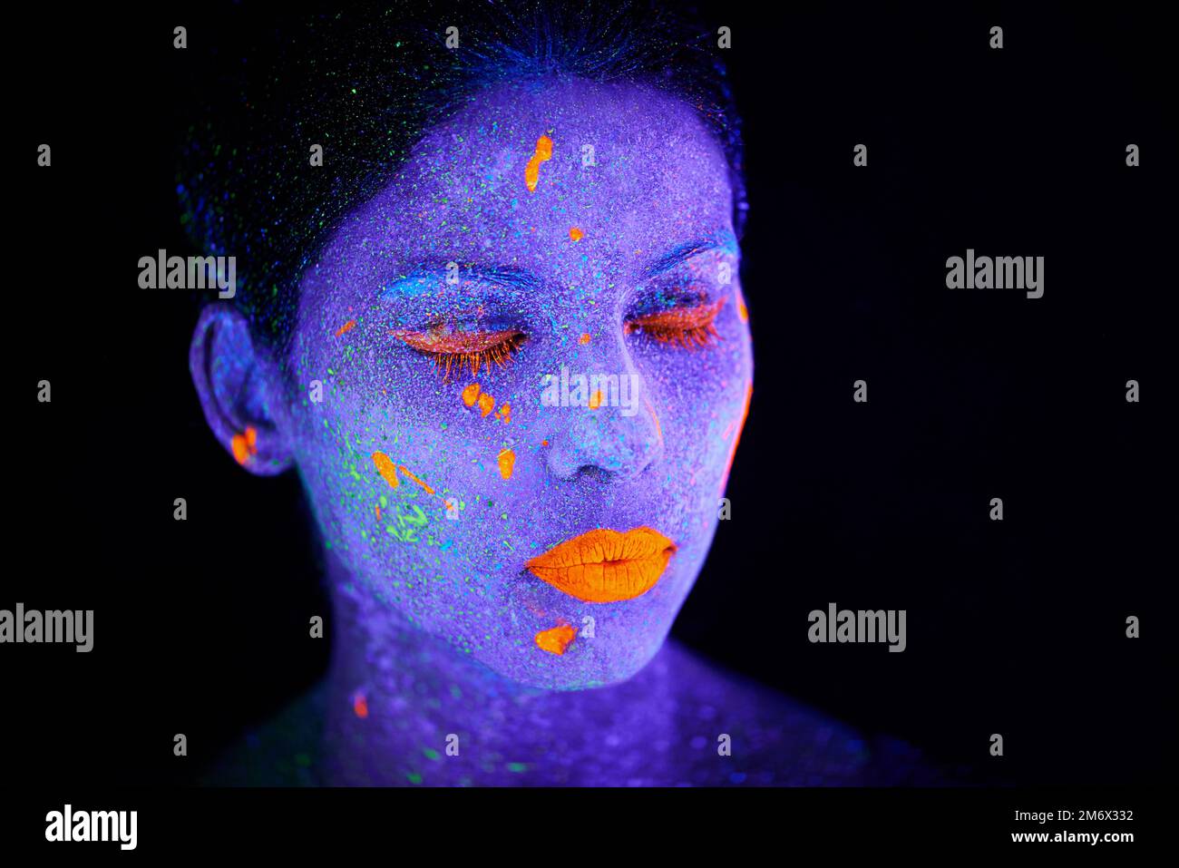 Schönheit in Neon. Eine junge Frau, die mit Neonfarbe im Gesicht posiert. Stockfoto