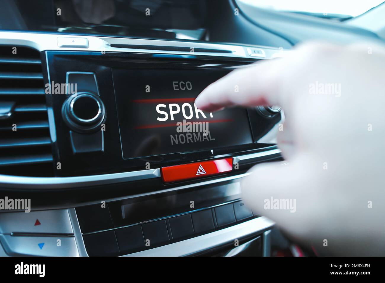 Der Fahrer wählt manuell einen Fahrmodus auf einem Touchscreen-Display in einem Fahrzeug aus. Stockfoto