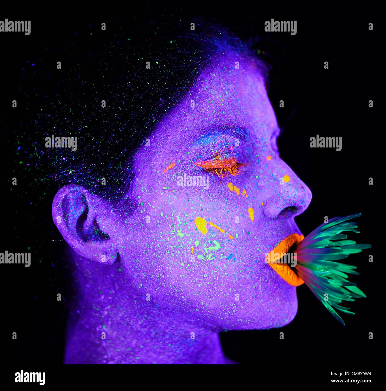 Bizarre Schönheit. Eine junge Frau, die mit Neonfarbe im Gesicht posiert. Stockfoto