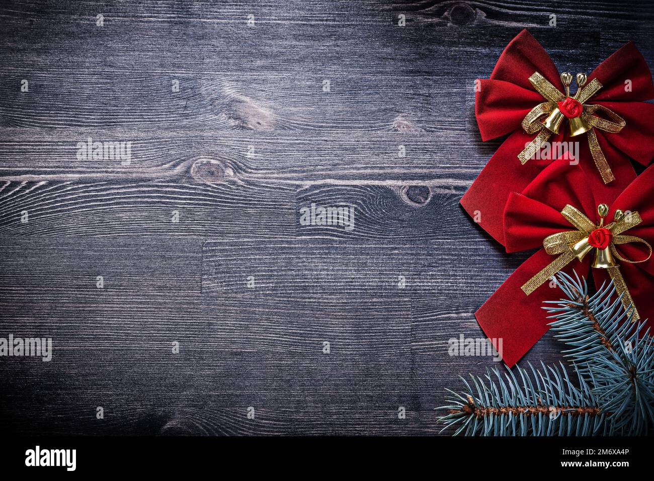 Weihnachtskonzept: Rote Schleife mit Glocken und Tannenzweig. Stockfoto