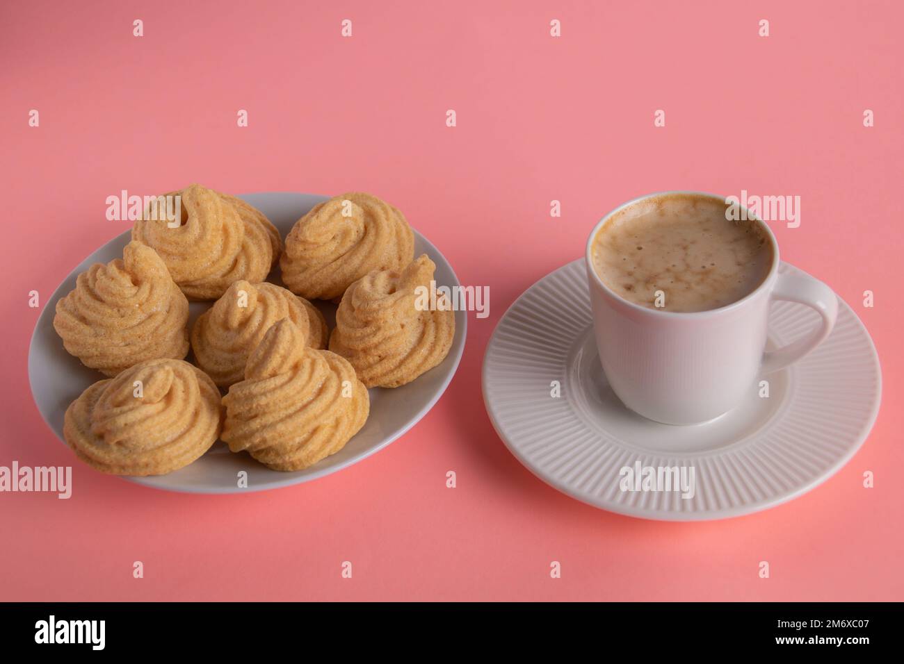 Fotokuchen neben einer Tasse Kaffee auf einer Untertasse auf pinkfarbenem Hintergrund Stockfoto
