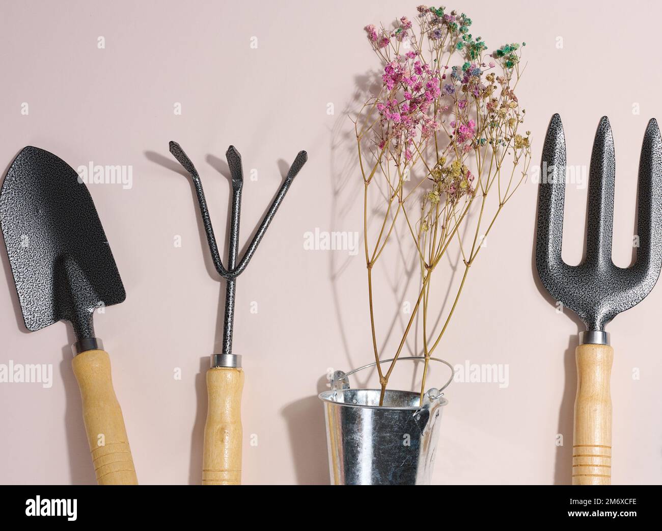 Gartenwerkzeuge zur Beetbearbeitung im Garten auf beigefarbenem Hintergrund Stockfoto