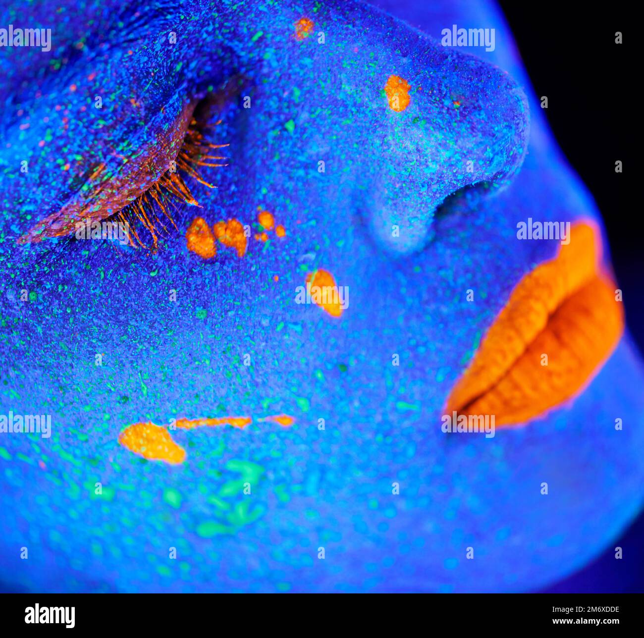 Blühende Fantasien. Eine junge Frau, die mit Neonfarbe im Gesicht posiert. Stockfoto