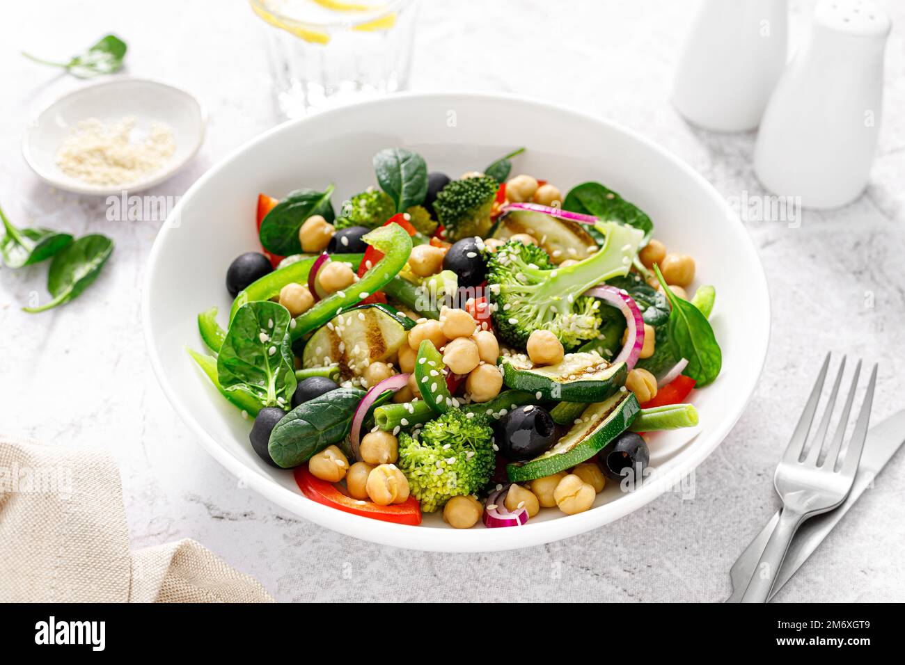 Kichererbsen- und Spinatsalat mit veganem Gemüse mit Brokkoli, süßem Pfeffer, Oliven und gegrillter Zucchini. Mediterrane Ernährung, gesunde Ernährung Stockfoto