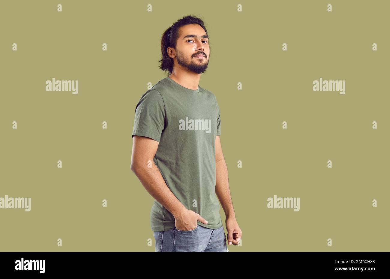 Attraktiver, selbstbewusster und stolzer indischer junger Mann in lässiger Kleidung mit Khaki-Hintergrund. Stockfoto