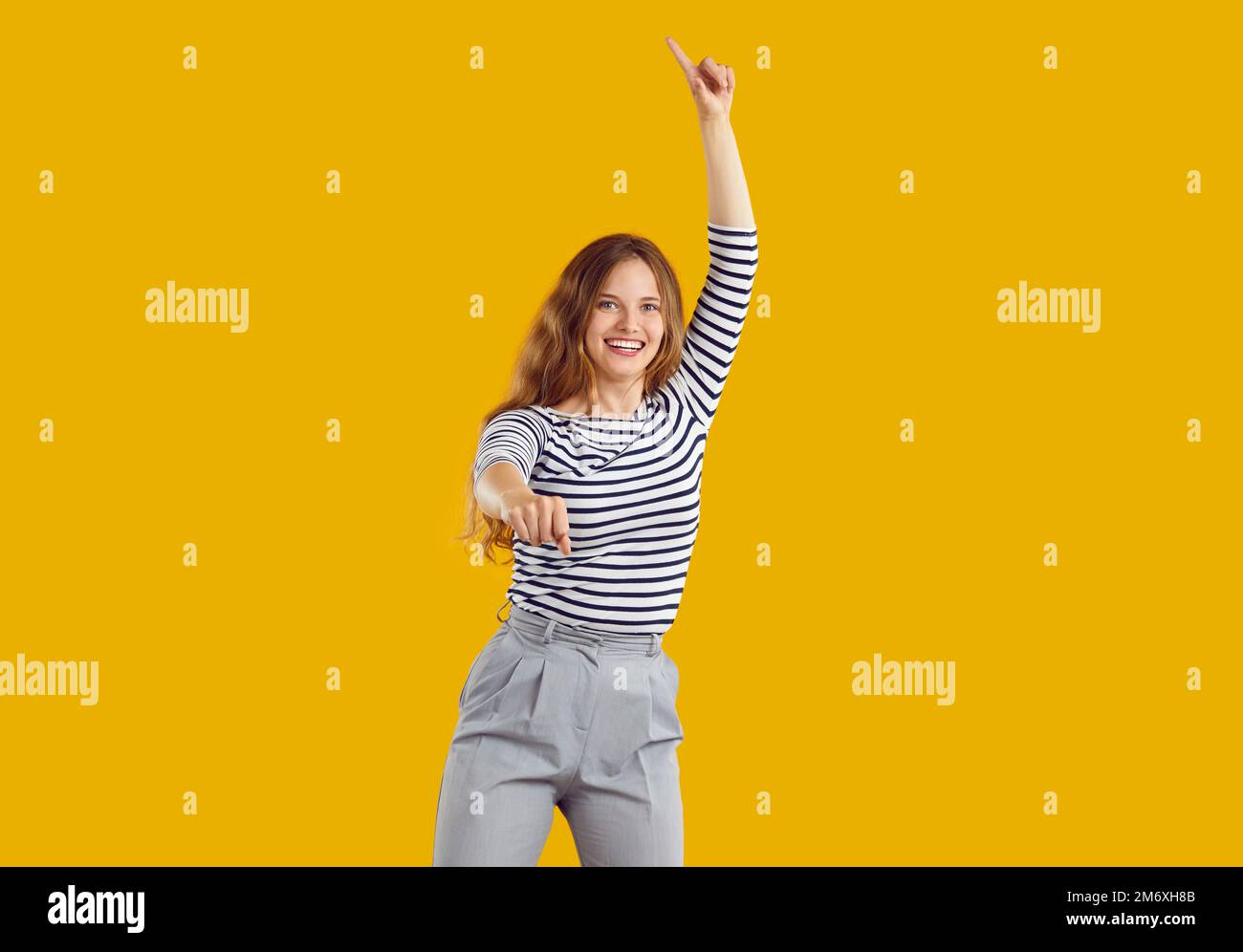 Porträt eines fröhlichen, lustigen jungen Mädchens, das tanzt und springt, isoliert auf gelbem Hintergrund Stockfoto