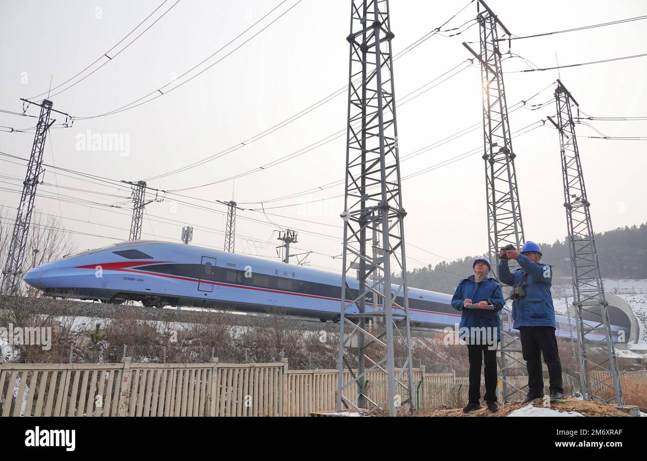 YANTAI, CHINA - 6. JANUAR 2023 - Mitarbeiter von Stromversorgungsunternehmen verwenden Infrarot-Thermometer, um eine Linie zu testen, die an der Stromversorgung einer Hochgeschwindigkeitsbahn in beteiligt ist Stockfoto