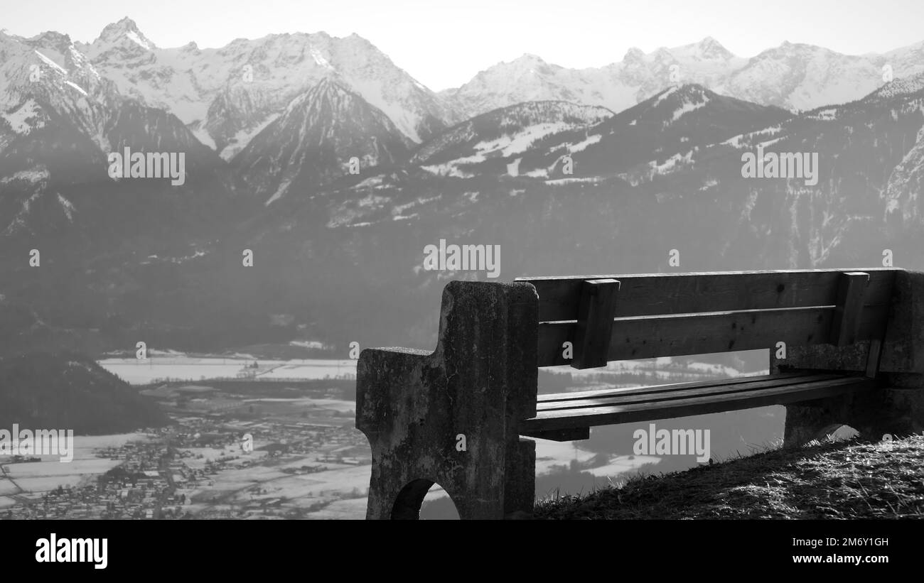 Bank auf einem Hügel mit Blick auf die alpen im Winter in Schwarz-Weiß Stockfoto
