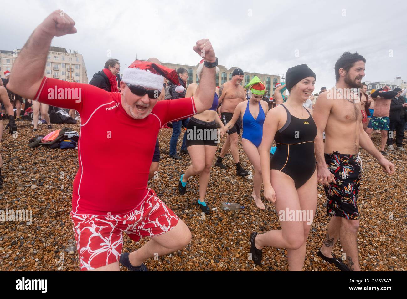 Hunderte von Schwimmern gehen am ersten Weihnachtsfeiertag am Brighton Beach mit einem belebenden Bad auf ein turbulentes Meer. Brighton, Stockfoto