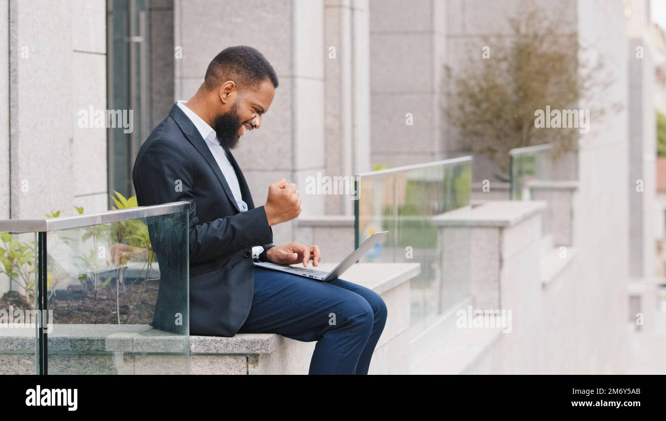 Afroamerikanischer erfolgreicher Angestellter aus ethnischen Gründen Unternehmer Executive Arbeitgeber Ethnischer Geschäftsmann, der mit einem Laptop im Freien in der Nähe des Firmenbüros arbeitet Stockfoto