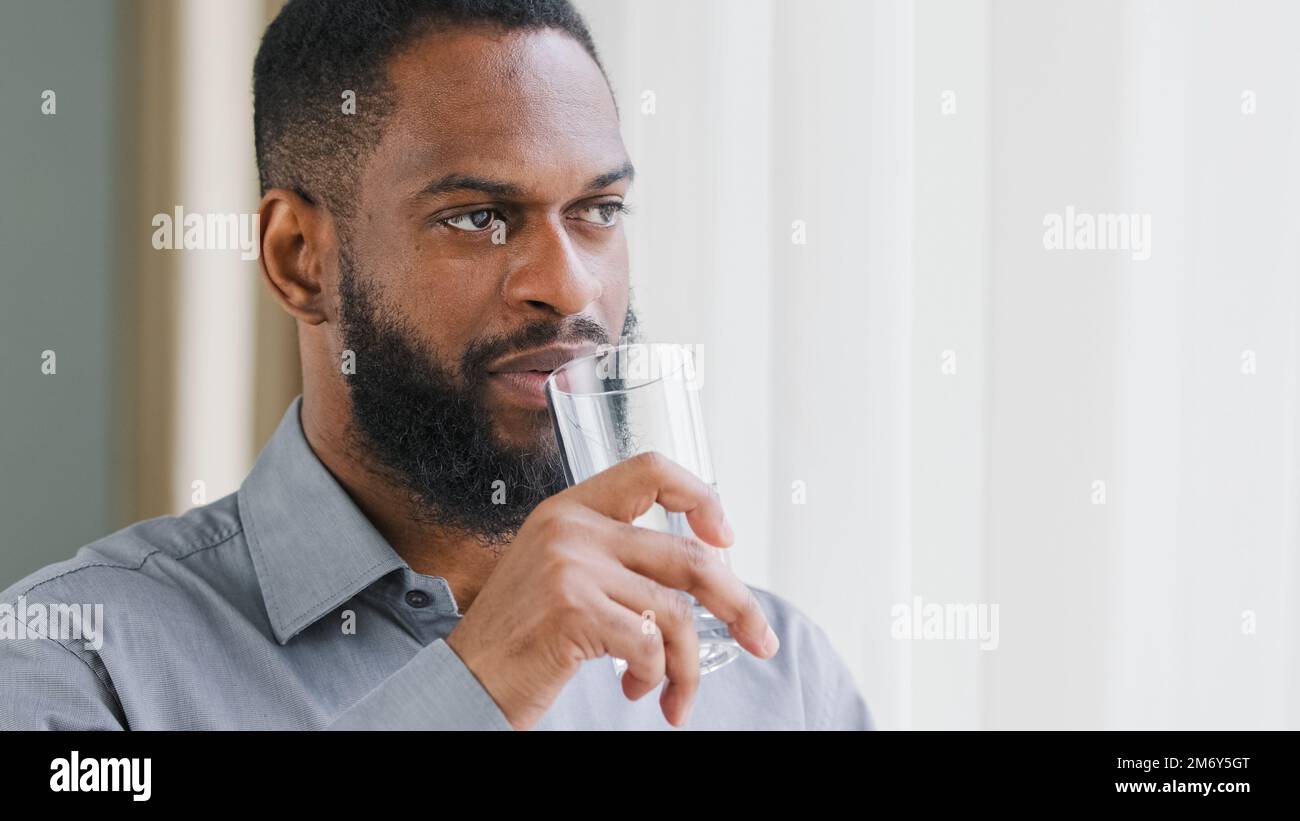 Erwachsener, mit Perlen bestückter afroamerikanischer Typ, CEO, Angestellter, Unternehmer, ethnischer Geschäftsmann, mit Glas, trinken kaltes Wasser. Gesunder Arbeiter Stockfoto