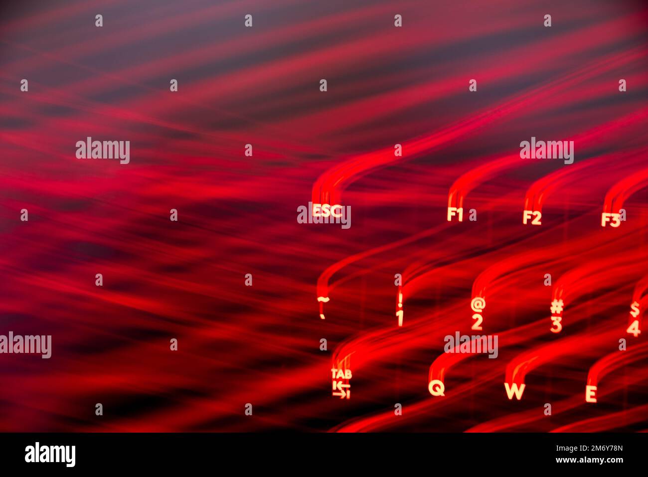 Helle Malerei auf Tastaturbuchstaben. Wunderschöner, farbenfroher Hintergrund. Lichtermalerei mit langer Belichtung. Rote gekrümmte Linien in leuchtendem Neon auf schwarzem Hintergrund. Stockfoto