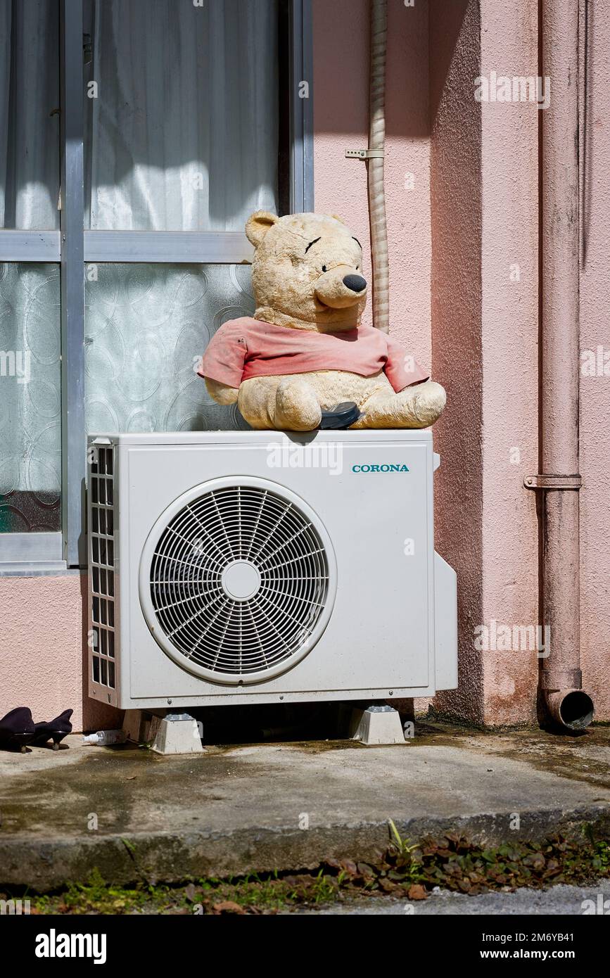 Winnie-the-Puuh Teddybär sitzt auf einer Corona Klimaanlage; Okinawa, Japan Stockfoto