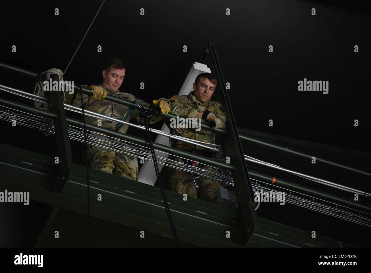 Die Armeebediensteten Shawn Parks und Jamie Koopman blicken von den Dachsparren des Tyson Events Center in Sioux City, Iowa hinunter, während sie sich am 10. Mai 2022 über den Rand des Laufstegs abseilen. Die beiden Soldaten der Nationalgarde von Iowa wurden beauftragt, zu Beginn der Playoff-Auseinandersetzung der Sioux City Musketeers Hockey Western Conference am Dienstagabend einen Puck zu liefern. USA Air National Guard Foto Senior Master Sgt. Vincent De Groot Stockfoto