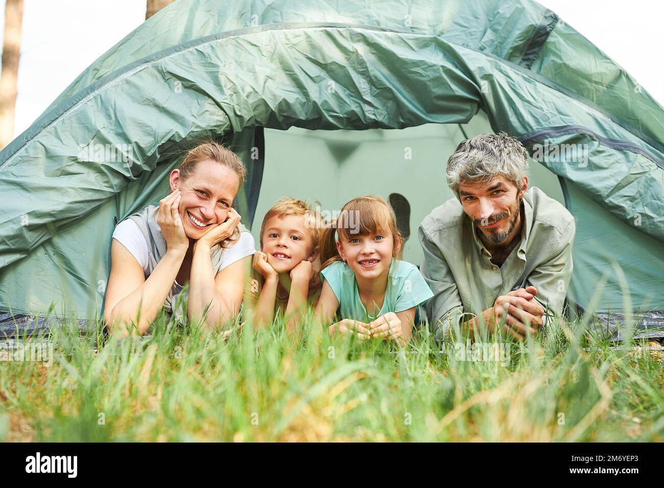 Glückliche Familie mit zwei Kindern im Zelt, Camping in der Natur im Sommer Stockfoto