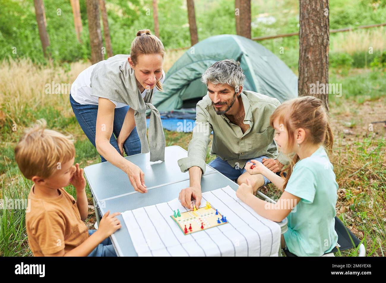 Mutter und Vater spielen Brettspiel mit Kindern auf dem Campingplatz Stockfoto