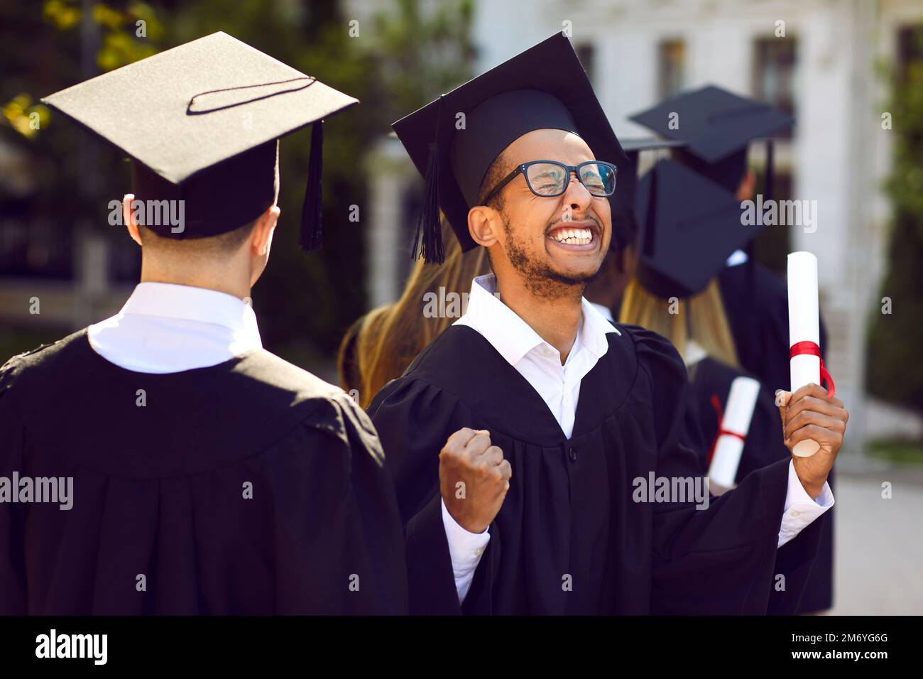 Glücklicher, aufgeregter Universitätsabschluss feiert und amüsiert sich bei seiner Abschlusszeremonie Stockfoto