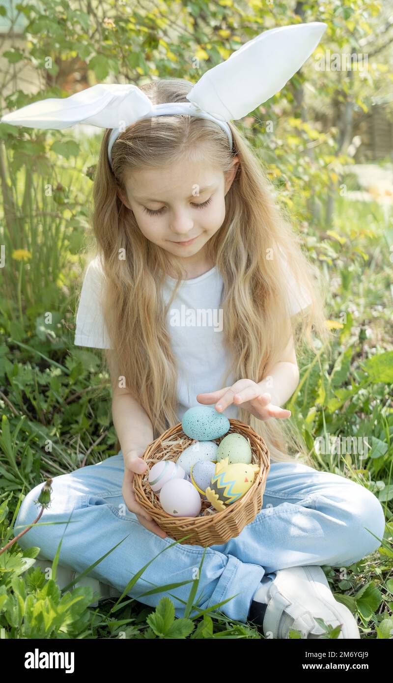 Süßes kleines Kind tragen häschenohren am Ostersonntag. Mädchen mit Korb mit bemalten Eiern. Stockfoto