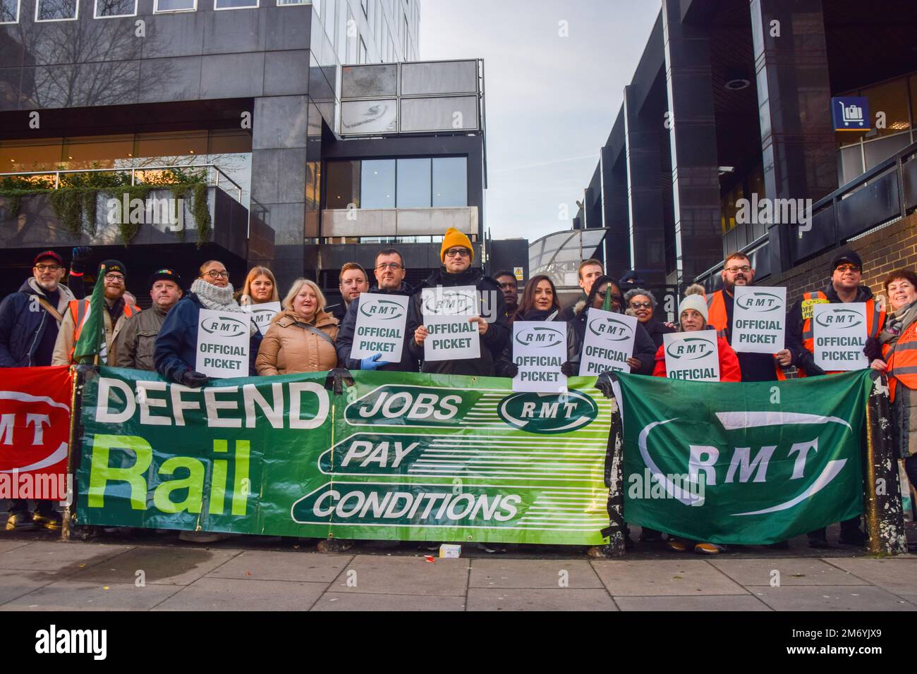 London, Großbritannien. 06. Januar 2023. Bahnarbeiter mit offiziellen Streikposten stehen hinter einem Banner „Defense Rail Jobs, Pay, Conditions“ (Stellen, Bezahlung, Bedingungen verteidigen) auf der RMT-Streikposte vor Euston Station, während die nationalen Streiks im Vereinigten Königreich weitergehen. Kredit: SOPA Images Limited/Alamy Live News Stockfoto