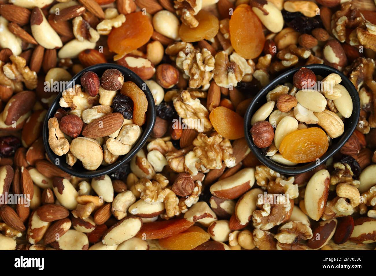 Mischen Sie Nüsse und getrocknete Früchte auf einem Holzbrett und in einer Schüssel. Gesunde Süßigkeiten. Stockfoto
