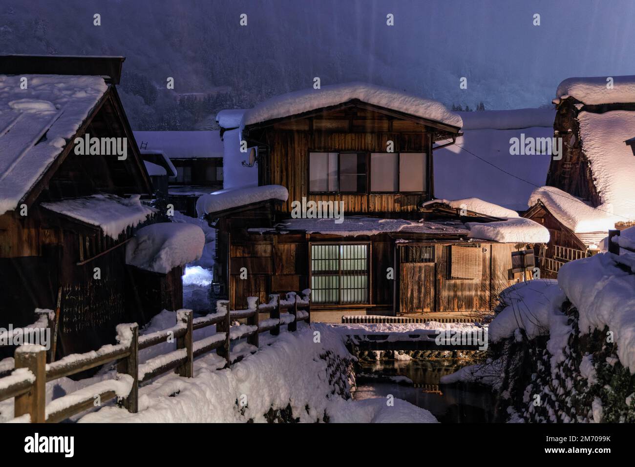 Bei Nacht fällt heftiger Schnee auf traditionelle Holzhäuser im japanischen Dorf Stockfoto