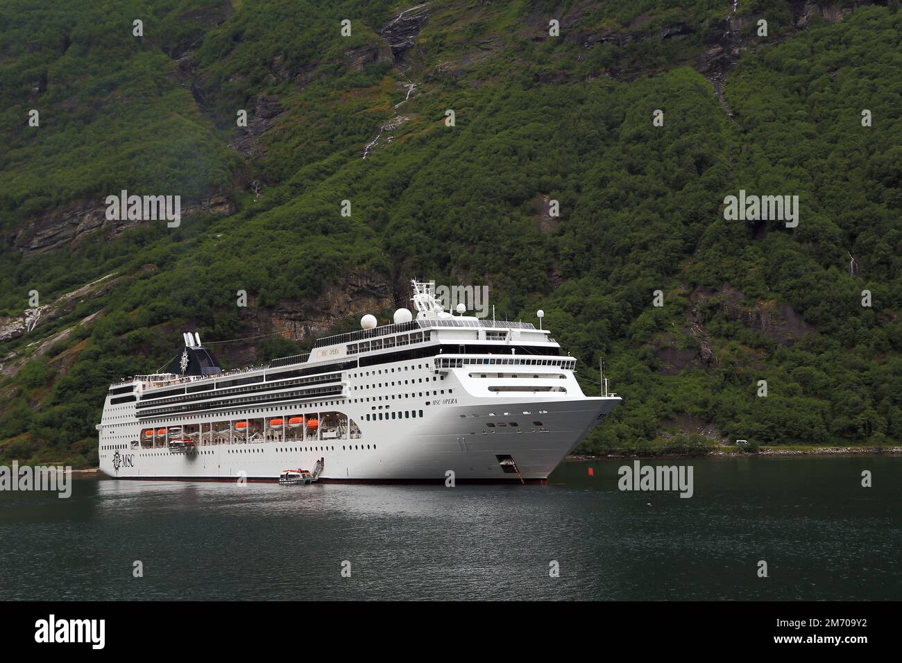 GEIRANGER, NORWEGEN - 6. JULI 2016: Das Schiff MSC Opera steht vor Anker in Geiranger Fjord in der Nähe der Stadt Geiranger. Stockfoto