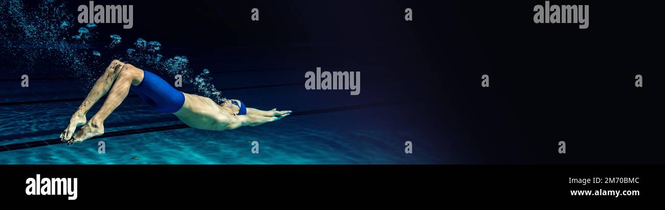 Dynamisches Porträt eines jungen Mannes, professionelles Schwimmertraining im Innenpool. Tieftauchen. Geschwindigkeit. Banner Stockfoto