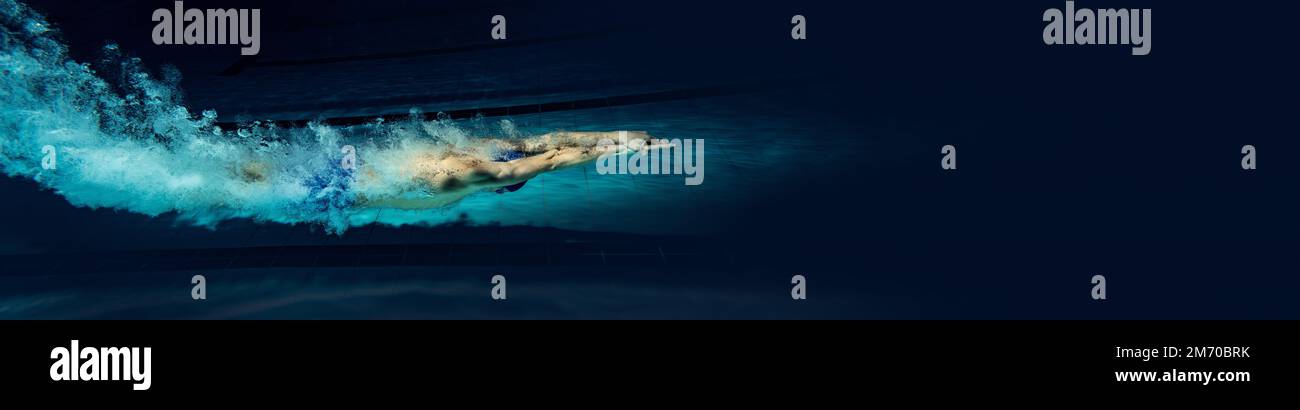 Dynamisches Porträt eines jungen Mannes, professionelles Schwimmertraining im Innenpool. Steigende Geschwindigkeit. Banner Stockfoto