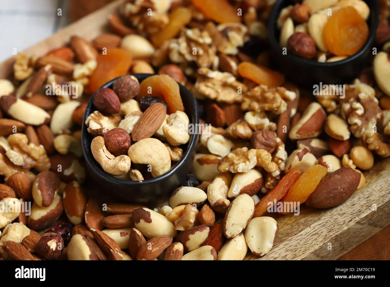 Mischen Sie Nüsse und getrocknete Früchte auf einem Holzbrett und in einer Schüssel. Gesunde Süßigkeiten. Stockfoto