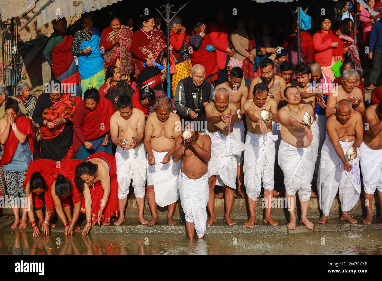 Nepal. 6. Januar 2023. Nepalesische Anhänger bieten der Sonne, auch bekannt als Arga, am Ufer des Hanumante River, Bhaktapur, Wasser an, anlässlich des Beginns von Shree Swasthani Brata Katha, einem einmonatigen Festival, das der Göttin Swasthani und dem Gott Madhav Narayan am Freitag gewidmet ist. Während des einmonatigen Geschichtenerzählerrituals werden die Geschichten von Göttin Swasthani, Gott Shiva und anderen Göttern erzählt, während die Gläubigen die Heilige Schrift vortragen und für das Wohlergehen ihrer Ehepartner beten. Die Rituale im Zusammenhang mit der Swasthani Katha finden am Flussufer in verschiedenen Hindu-Schreinen statt Stockfoto