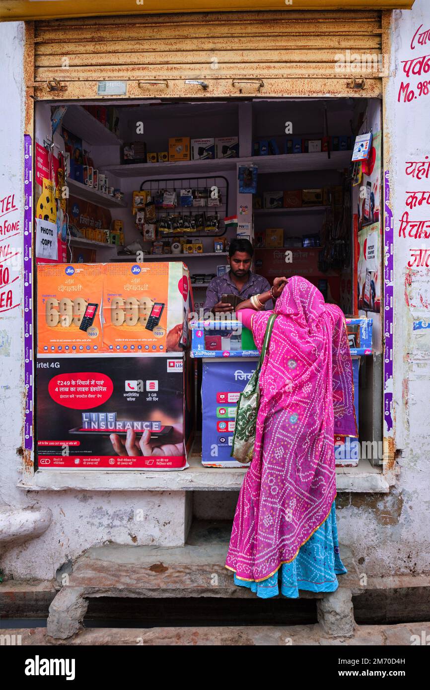 Pushkar, Indien - 7. November 2019: Der Anbieter von Straßenelektronik lädt Frauen-Mobiltelefone in der Straße von Pushkar, Rajasthan, Indien auf Stockfoto