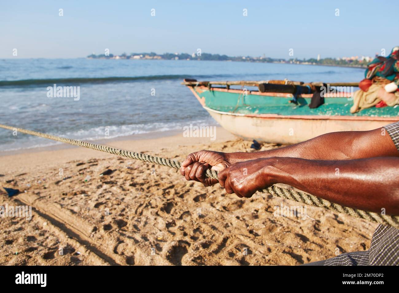 Nahaufnahme starker Hände beim Ziehen eines Seils mit Fischernetz aus dem Meer. Ist auf harte Arbeit, Beharrlichkeit und Stärke ausgerichtet. Stockfoto