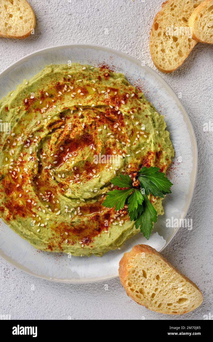 Avocado hummus gewürzt mit Sesam, Paprika und Petersilie. Das Gericht wird mit Toast serviert. Stockfoto