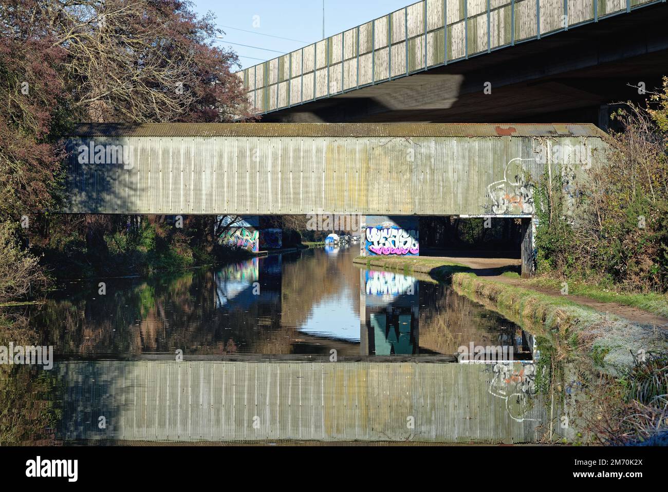 Brutalistische Industriestrukturen, die über den River Wey Navigationskanal führen, an einem sonnigen Wintertag, New Haw Surrey England UK Stockfoto